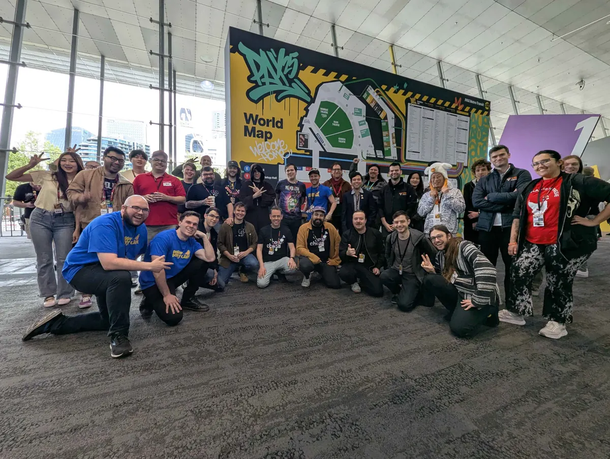 A crowd of Australian indie developers with exhibitor lanyards gathers in front of the PAX Australia world map wall.
